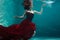 Beautiful girl in a red dress swims under water. amazing Underwater