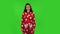 Beautiful girl in red fleece pajamas is standing, spreads out in a smile. Green screen