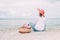 Beautiful girl in a red hat with picnic basket at the summer waterfront.