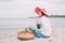 Beautiful girl in a red hat with picnic basket at the summer waterfront.