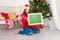 A beautiful girl in a red sweater in the children`s room near the Christmas tree with a new year`s interior holds a Board with