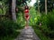 Beautiful girl in red swimsuit posing in tropical location with green trees. Young sports model in bikini with perfect