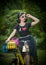 Beautiful girl with retro look wearing a black outfit having fun in park with bicycle. Outdoor lifestyle concept. Vintage