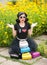 Beautiful girl with retro look wearing a black outfit having fun in park displaying a lot of colored bags. Fashionable brunette