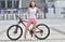 Beautiful girl riding a bicycle in a city. Standing with bike. Active people. Outdoors