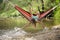 Beautiful girl riding in a hammock over the water.