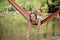 Beautiful girl riding in a hammock over the water.