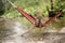 Beautiful girl riding in a hammock over the water.