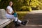 Beautiful girl on roller skates in park sits on bench and drinks water