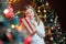 Beautiful girl in the room near the festive Christmas tree holds a gift