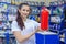 Beautiful girl saleswoman offers an extinguisher in an auto parts store. Compliance with travel safety regulations