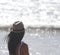 Beautiful girl, seen from behind, with hat who look the sea. Sea in the background.