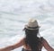 Beautiful girl, seen from behind, with hat who look the sea. Sea in the background.