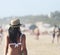 Beautiful girl, seen from behind, with hat who walk on the beach. People in the background.