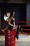 Beautiful girl in sexual leather clothes sits on red barrel in the centre boxing ring.