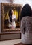 The beautiful girl in a short white dress looking into mirror