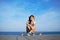 Beautiful girl sits on longboard with amazing horizon of sea on background