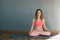 A beautiful girl sits on a yoga mat in a lotus position in the classroom. Sports, fitness, yoga. Space for text