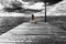 A beautiful girl is sitting alone on the river pier against the backdrop of thunder clouds and looks into the distance.