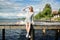 A beautiful girl is sitting alone on a river pier under the clear sun and looking into the distance, hiding behind her hand from t