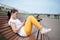 Beautiful girl sitting on bench in park with phone in hands