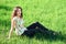 Beautiful girl sitting on a glade in the woods, bright sun and shadows on the grass