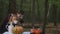 Beautiful girl sitting at table in forest drinking tea as vampire scaring kid. Pretty Caucasian child celebrating