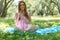 Beautiful girl sitting under the tree in nature and drinking fresh bottled water on sunny summer day.