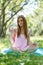 Beautiful girl sitting under the tree in nature and drinking fresh bottled water on sunny summer day.