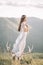 Beautiful girl with slender figure in a long winding dress profile, tulle, veil, nature, mountains, forest, deer skull with horns