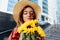 Beautiful girl is smelling a bouquet of flowers of sunflowers. Hair fluttering in the wind. Sensual moment. Urban fashion woman