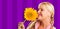 Beautiful Girl Smelling a Yellow Sunflower Against Purple Striped Background