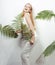 Beautiful girl smiles and laughs, dances in the tropical leaves. Chic white suit. Summer fashion. Happiness party in style total