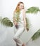 Beautiful girl smiles and laughs, dances in the tropical leaves. Chic white suit. Summer fashion. Happiness party in style total