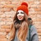 Beautiful girl smiling near brick red wall in winter day