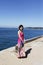 A beautiful girl is standing besides the beach with blue sea and cloud sky