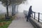 Beautiful girl standing on pedestrian walkway watching autumn mist