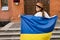 Beautiful girl standing in Ukrainian flag worried about war. Cute woman is feeling emotional pain after reading the news