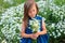 Beautiful girl stands in the field with daisies in summer