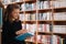 Beautiful girl is studying reading a book while standing on the floor among books in the bookshop