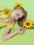 A beautiful girl with sunflowers in her blonde hair and a yellow baby manicure