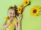 A beautiful girl with sunflowers in her blonde hair and a yellow baby manicure