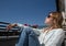 Beautiful girl in sunglasses sits in a chair on the balcony in the morning light