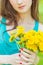 Beautiful girl in a Sunny summer day walking in the garden and keeps yellow dandelions in the hands