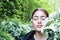 Beautiful girl surrounded by green plants and white flowers