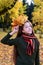 beautiful girl in sweater and scarf with wreath of yellow maple leaves on her head. Teenage girl walks through autumn park