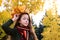 beautiful girl in sweater and scarf with wreath of yellow maple leaves on her head. Teenage girl walks in autumn park