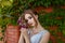 Beautiful girl in tender prom dress on brick wall and green ivy bush with flowers background. Female portrait