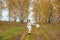 Beautiful girl in a traditional Slavic dress with a straw basket in her hands walks in the autumn forest