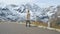 Beautiful girl traveler walks along Majestic Grossglockner Mountain Road in Austria, snow covered sharp peaks of the